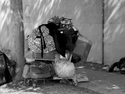 Monochromatic image of resting place of homeless person who's belongings are in a shopping cart.
