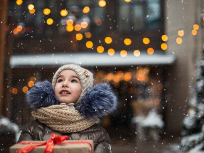 Portrait of joyful girl with a gift box for Christmas on a city street in winter