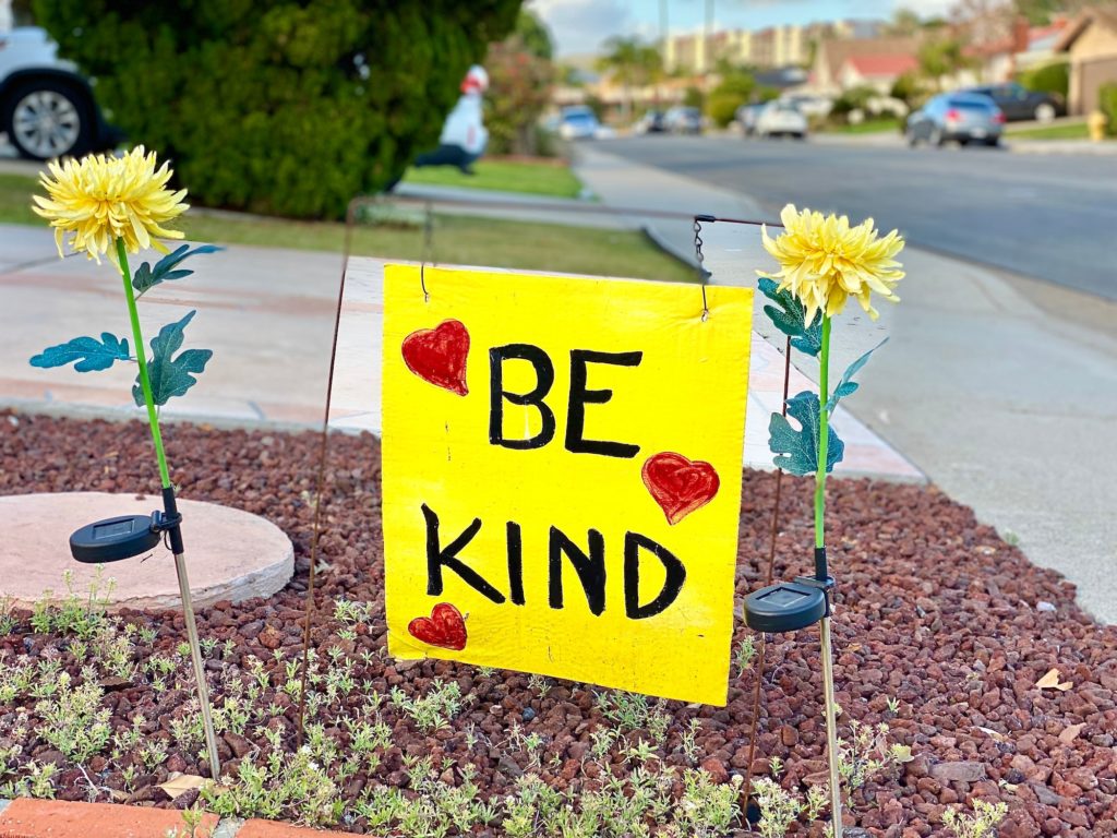 Neighborhood house, street sign that is reminding people to BE KIND to one another.
